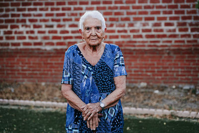 Portrait of woman standing against brick wall