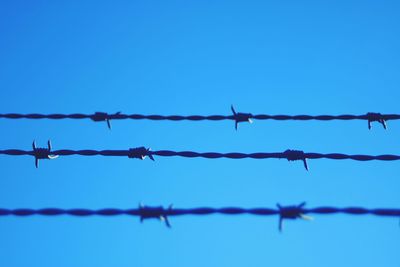 Low angle view of barbed wire against clear sky