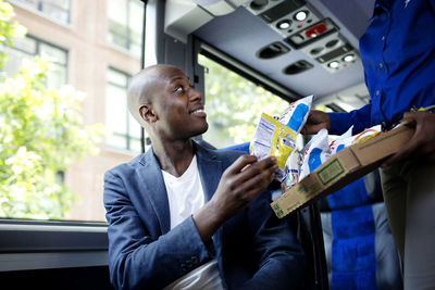 Happy man taking snacks from guide in bus