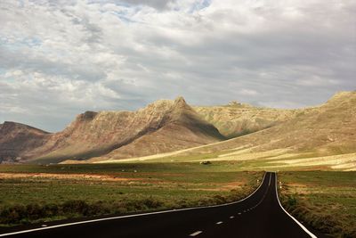 Scenic view of road by mountains against sky