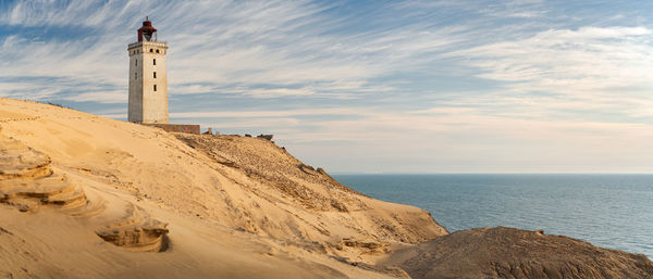 Lighthouse by sea against sky