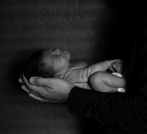 Midsection of father holding baby against wall