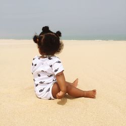 Full length of girl sitting on sand at beach