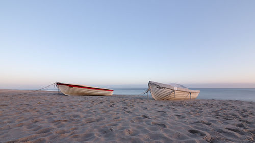 Deck chairs on beach against clear sky