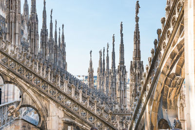 View to spires and statues on roof of duomo through ornate marble fencing. milan, italy