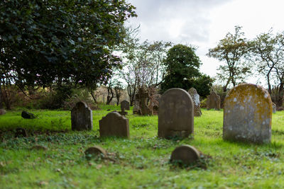 Stone cross in cemetery against sky