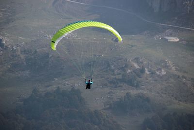 High angle view of people paragliding over mountain against sky