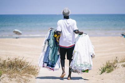 Vendor with dresses for sale walking on boardwalk at beach