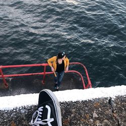 Low section of man standing on boat in sea