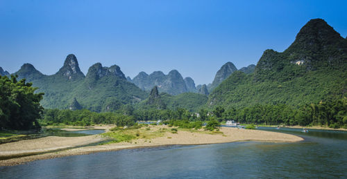 Scenic view of river amidst mountains against clear sky