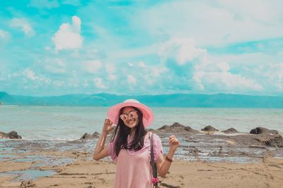 Full length portrait of woman standing on beach against sky