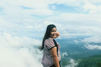 Young woman standing on mountain against sky