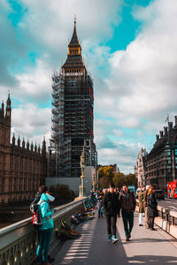 Low angle view of people standing on bridge in city