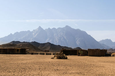 Basic built structure on land by mountains against sky