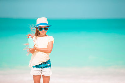 Man wearing hat standing at beach against sky