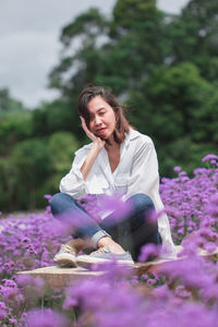 Young woman sitting on purple flowering plants