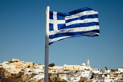 Flag against buildings in city against clear blue sky