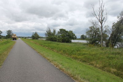 Road amidst field against sky