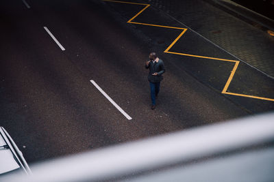 High angle view of businessman using mobile phone while walking on street in city