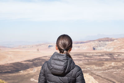 Rear view of woman standing on arid landscape