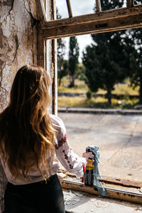 Rear view of woman standing by window at home