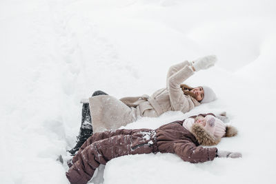 Joyful mother and daughter lying in the snow. high quality photo