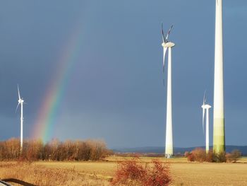 Wind turbines on field against sky