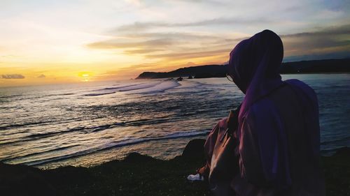 Man looking at sea against sky during sunset