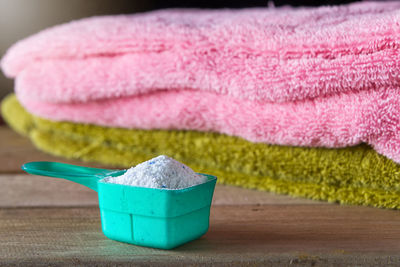 Close-up of laundry detergent in measuring cup against towels on table