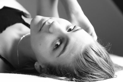 Close-up portrait of young woman lying on bed