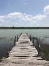 Wooden jetty on pier over lake against sky