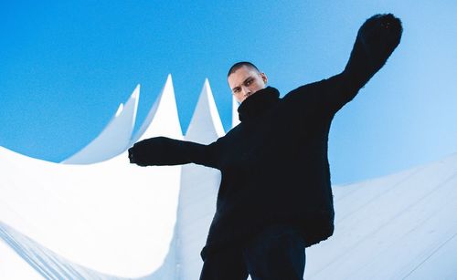 Low angle view of man standing against clear blue sky