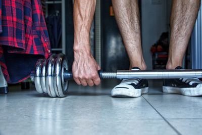 Low section of man lifting dumbbell in gym