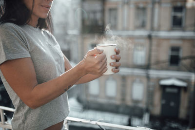 Midsection of woman holding coffee cup in city