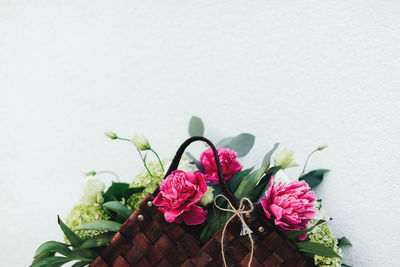 Beautiful pink flowers in the wooden basket on white background