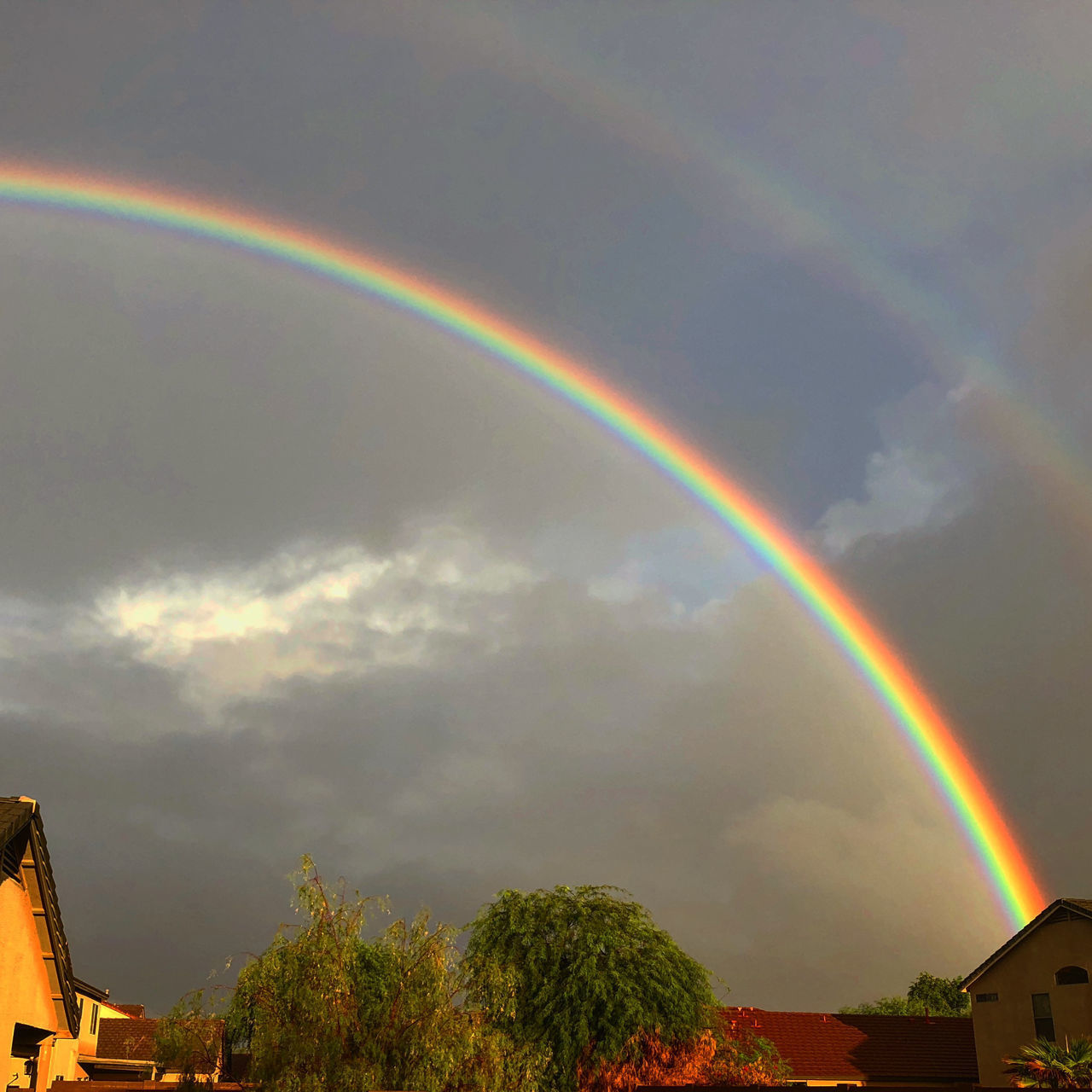 LOW ANGLE VIEW OF RAINBOW OVER BUILDING AND TREES AGAINST SKY