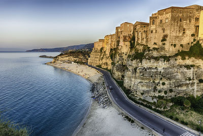 Scenic view of sea by mountain against sky