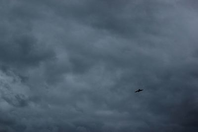 Low angle view of airplane flying against cloudy sky