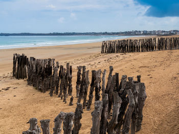 Panoramic view of wooden posts on beach against sky