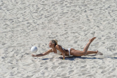 High angle view of friends lying on sand at beach