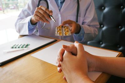 Midsection of doctor explaining medicines to patients at hospital