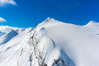 Scenic view of snowcapped mountains against blue sky