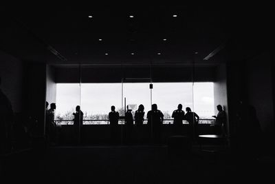 Silhouette people standing by window in bus