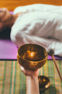 Cropped hands of woman playing singing bowl for customer in spa