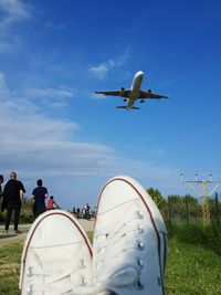 People at airport runway against blue sky