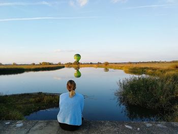 Rear view of woman against lake against sky