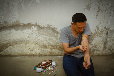 Man injecting syringe against wall