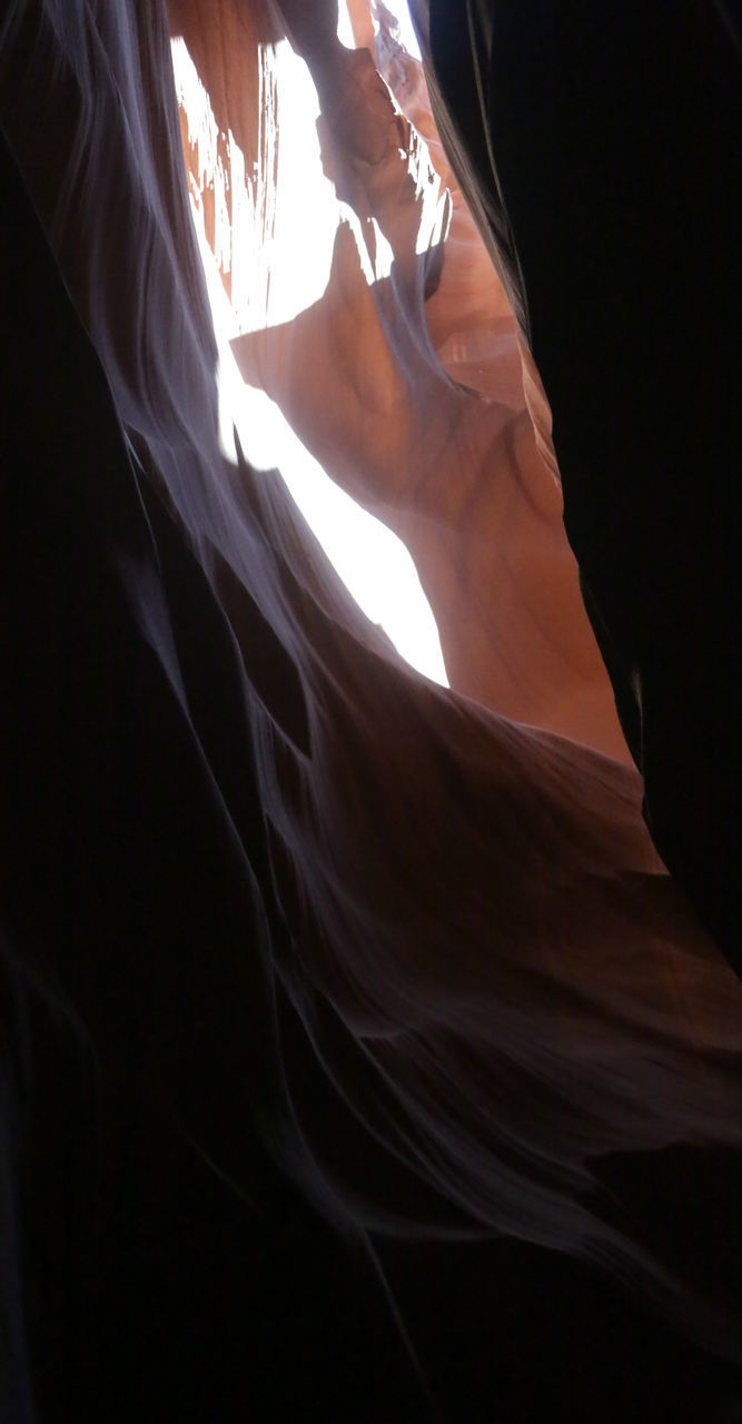 LOW ANGLE VIEW OF WOMAN STANDING AGAINST CURTAIN