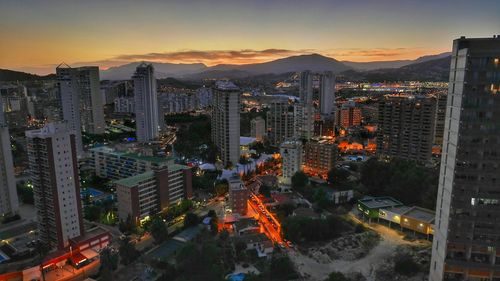 View of illuminated cityscape against sky at sunset