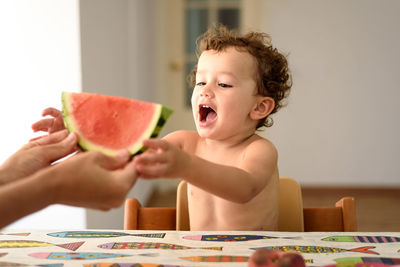 Shirtless girl holding watermelon at home